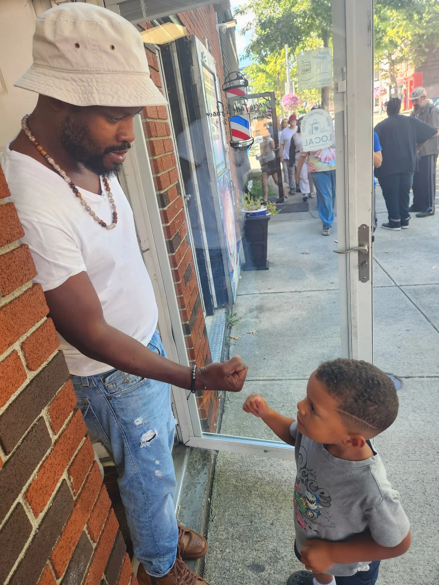 Maxx, the barber at Beacon Fade & Shave, fist-bumping a young client outside the shop on Main St in Beacon, NY